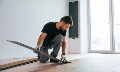 Fitting the planks. Man is installing new laminated wooden floor.