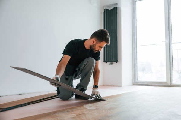 Fitting the planks. Man is installing new laminated wooden floor.