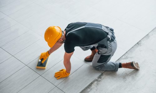Top view of man in grey uniform that installing plate indoors in modern big office at daytime.