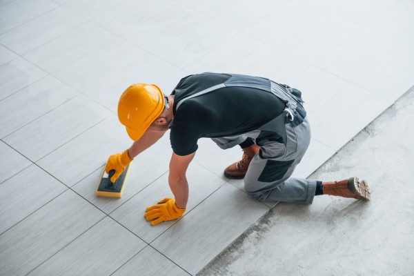 Top view of man in grey uniform that installing plate indoors in modern big office at daytime.